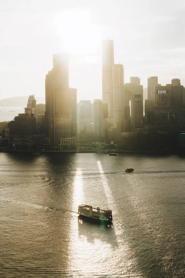 A ferry travels on water in front of city buildings.